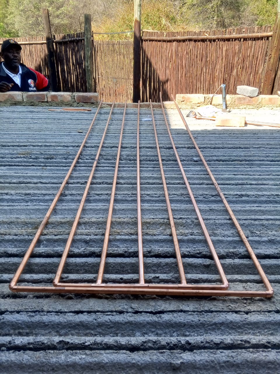 Copper piping frame being assembled on a brick structure